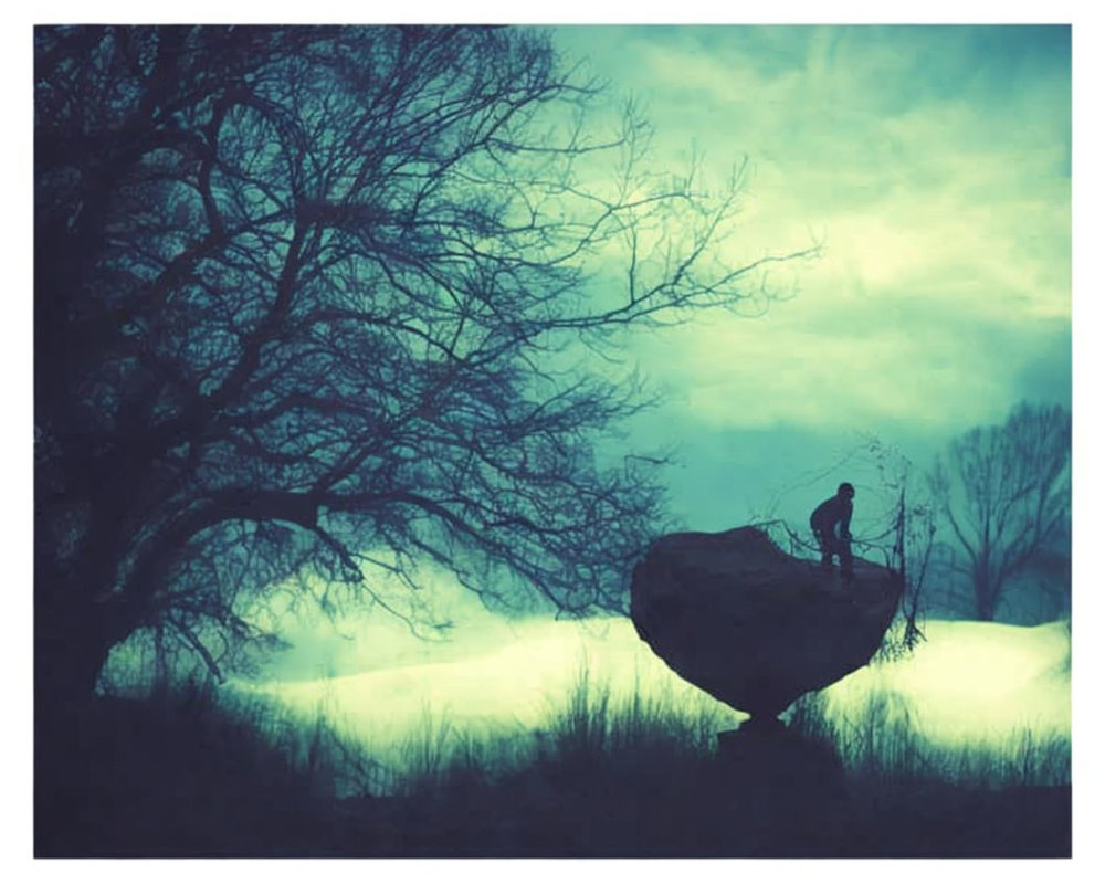 Silhouette of person fishing on rock in mystical, foggy landscape