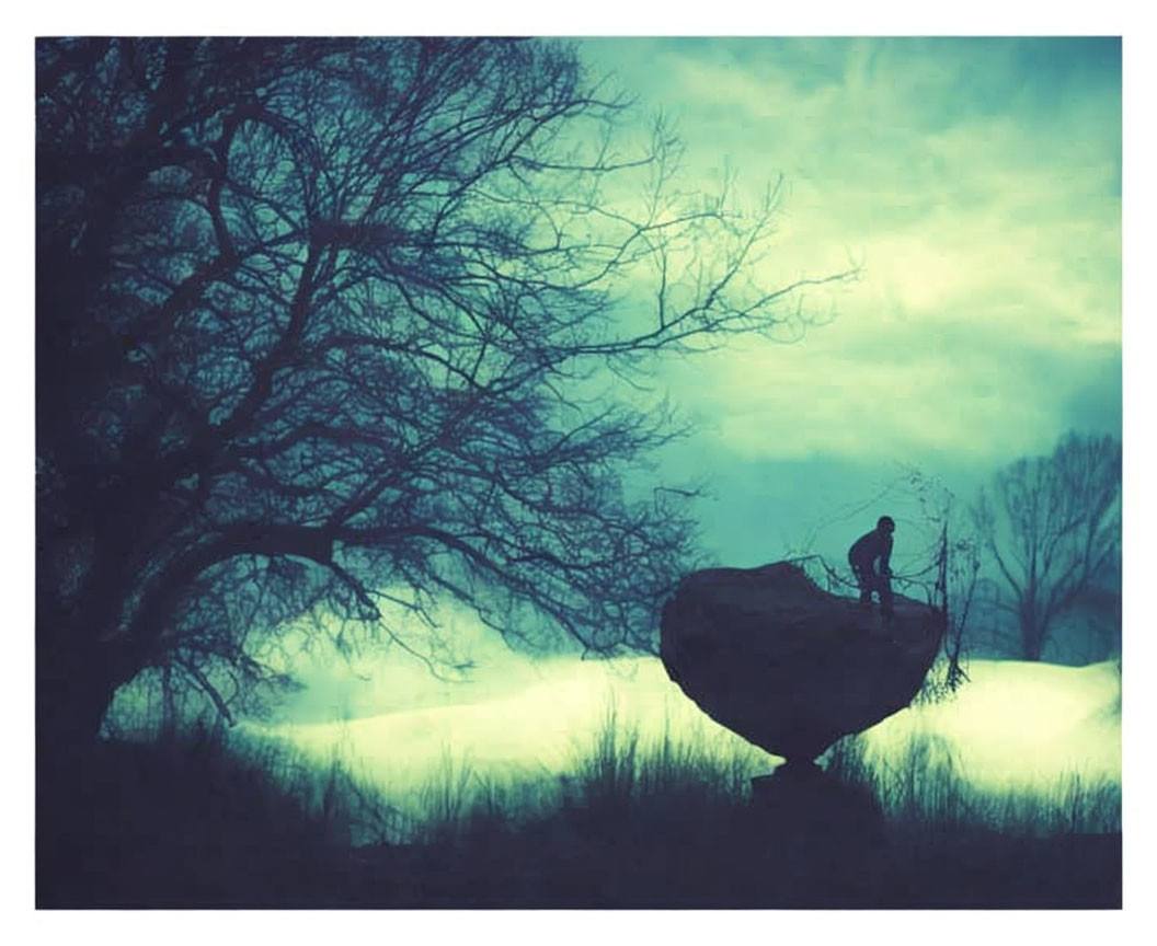 Silhouette of person fishing on rock in mystical, foggy landscape