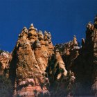 Surreal red rock formations with giant face, small figures, cracked blue sky