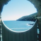 Circular Coastal Landscape View with Palm Trees, Houses, Hills, and Boat