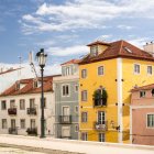 Vibrant streetscape with quaint houses, classic car, and birds in clear skies