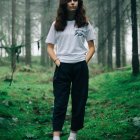 Stylish young woman in striped shirt and culottes in whimsical forest