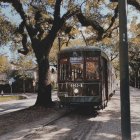 Vintage-style illustration of tram on tree-lined tracks with retro car, mid-20th century design