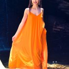 Fashionable Woman in Orange Floral Dress with Accessories on Vibrant Background