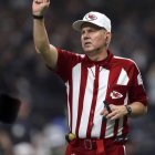 Sports game referee in striped shirt making call with blurred crowd.