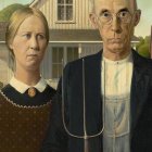 Portrait of stern couple with pitchfork in front of farmhouse