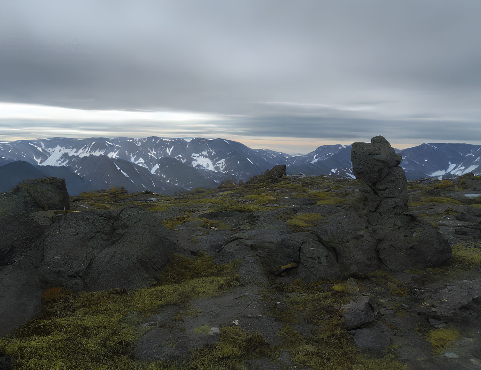 Tranquil mountain landscape with moss-covered rocks and snow-capped peaks