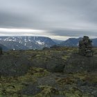 Tranquil mountain landscape with moss-covered rocks and snow-capped peaks