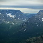 Scenic mountain range with rugged peaks and green valleys under cloudy sky