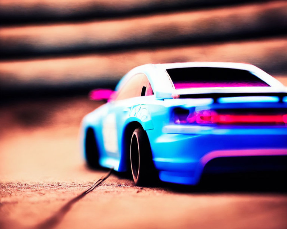 Miniature blue toy car with pink underglow on textured surface in motion.