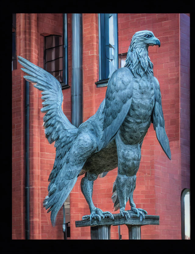 Detailed metal griffin sculpture in front of red brick building