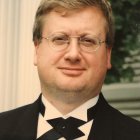 Man in Glasses with Beard in Tuxedo Portrait Against Blurred Tree Background