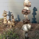 Balanced stacked rocks on rugged terrain with golden pedestal under cloudy sky