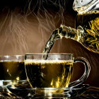 Steaming tea poured into cup with dark background, spoon and leaves in foreground