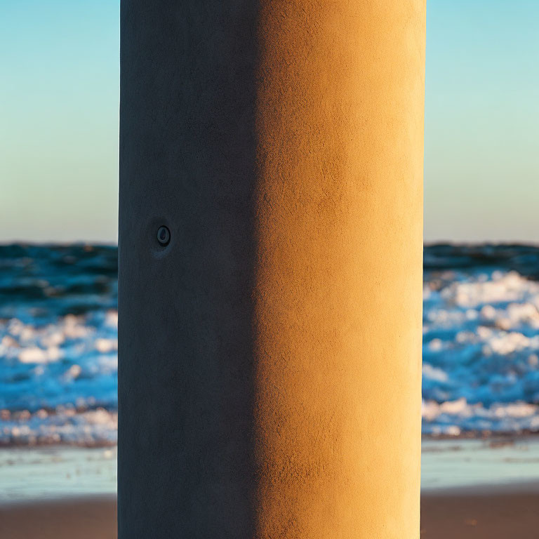 Textured pillar against ocean waves at sunset