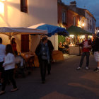 Traditional attire shoppers at dusk in historical town market.