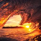 Women with flowing hair by sunset-lit sea, one facing viewer, other looking down.