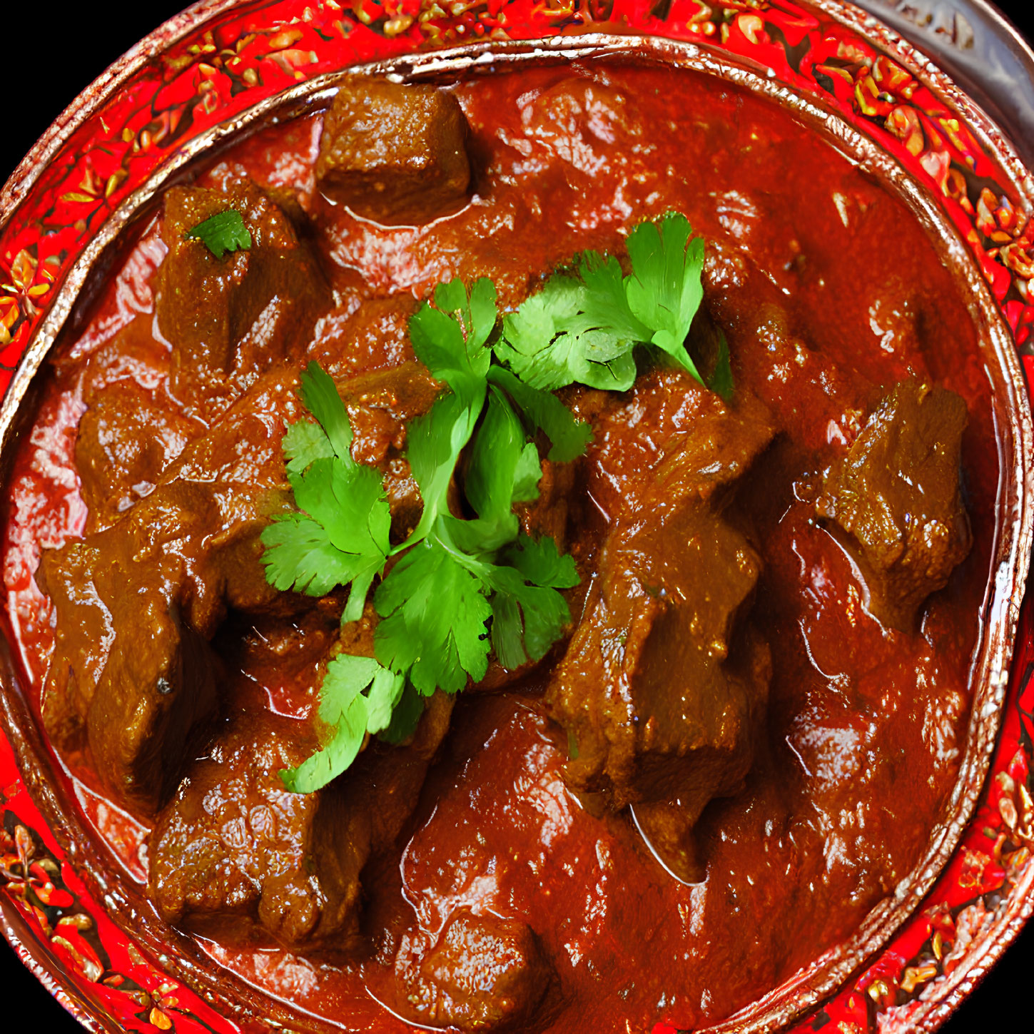 Savory red curry with meat chunks and cilantro in decorative dish