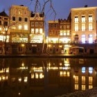 Impressionist-style Night Scene Painting with Buildings and Water Reflections