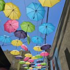 Vibrant umbrellas and white splashes under blue sky with old building