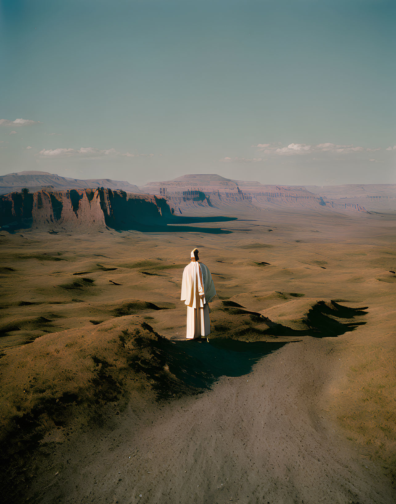 Solitary figure in vast desert landscape with towering cliffs