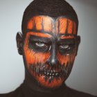 Person with Jack-o'-lantern Face Paint and Glowing Eyes