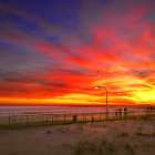 Vibrant beach sunset watercolor painting with blue and crimson skies.