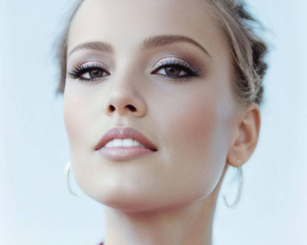 Woman in Pink Top with Hoop Earrings and Makeup on Light Background