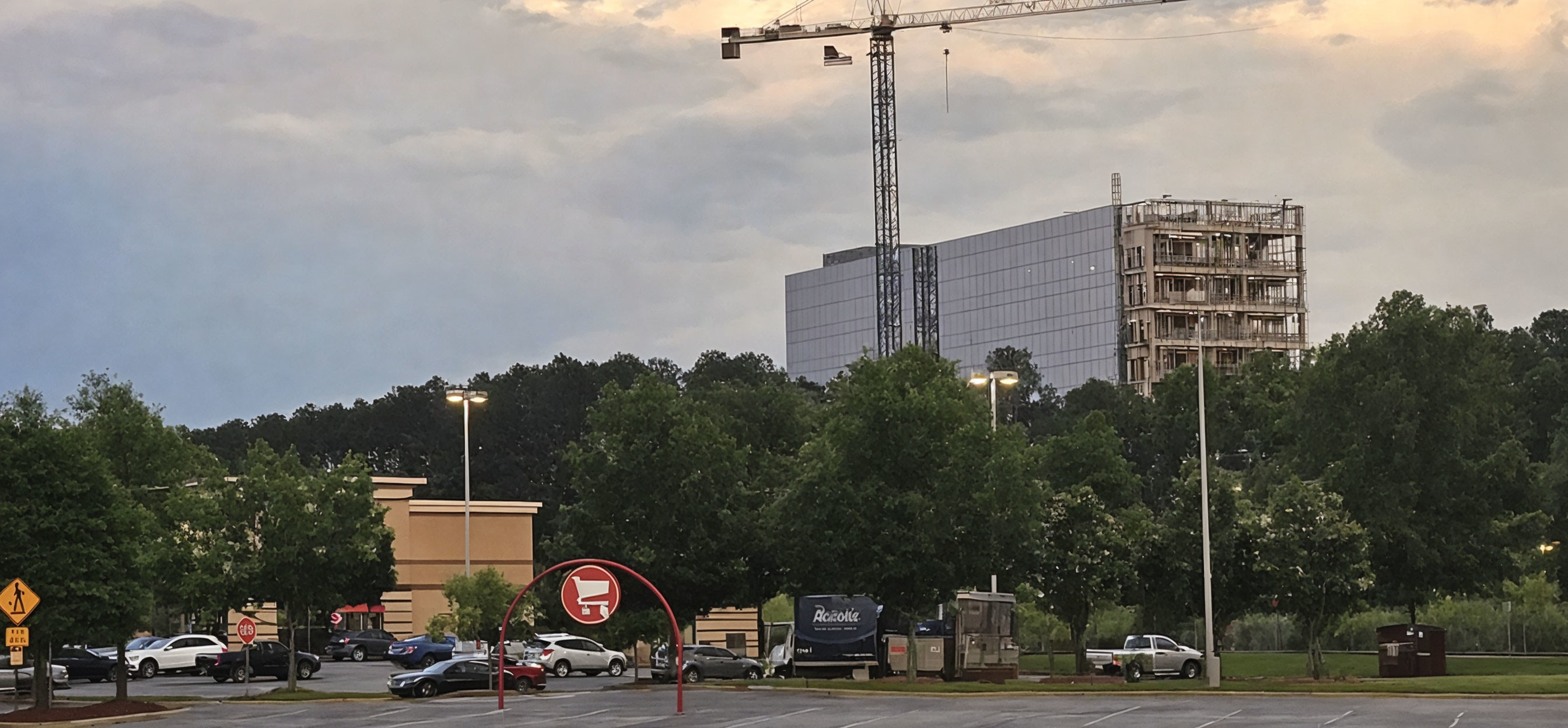 Parking lot with cars, QuikTrip sign, construction site with crane, cloudy sky.