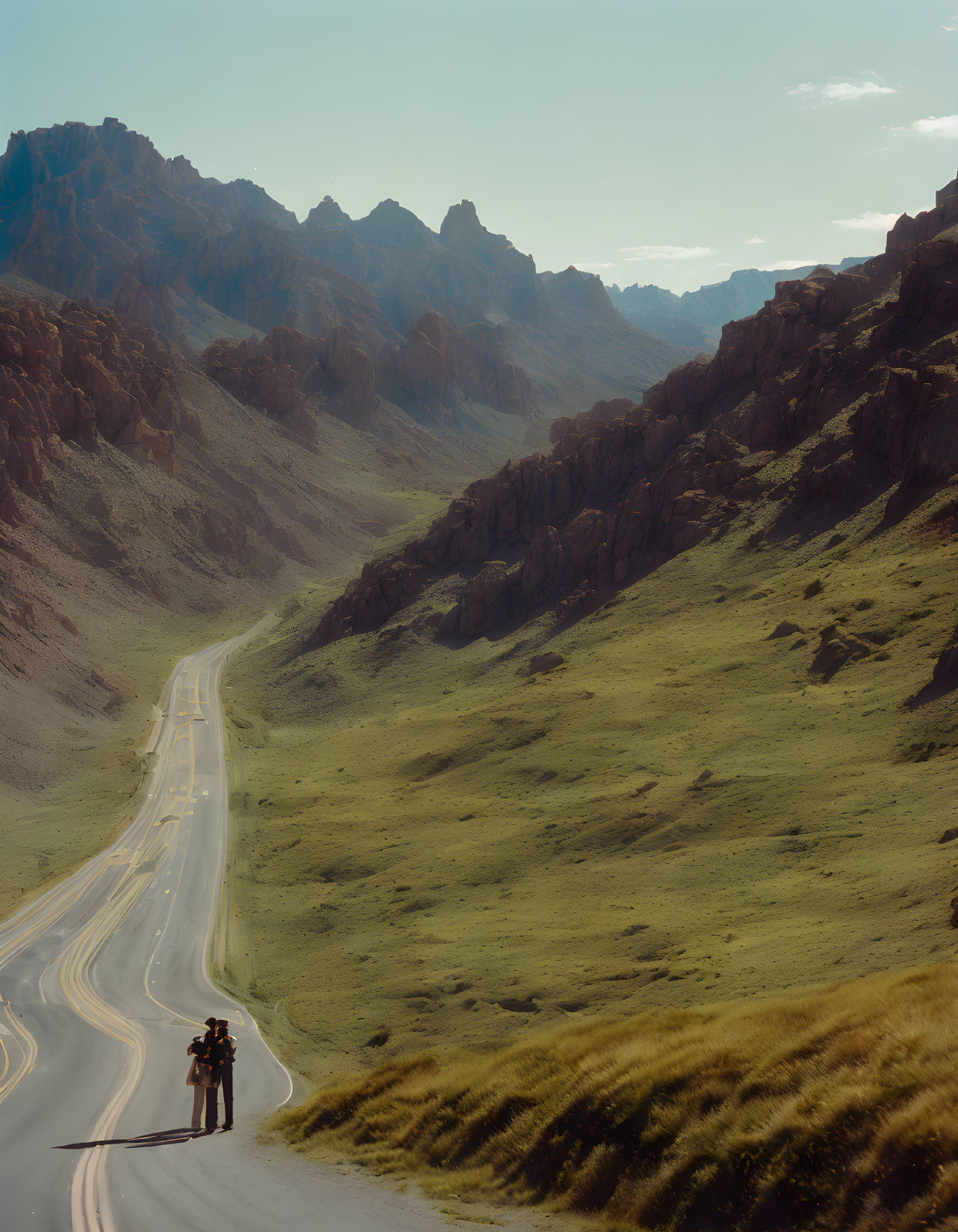 Winding road through rugged mountains with person taking photo