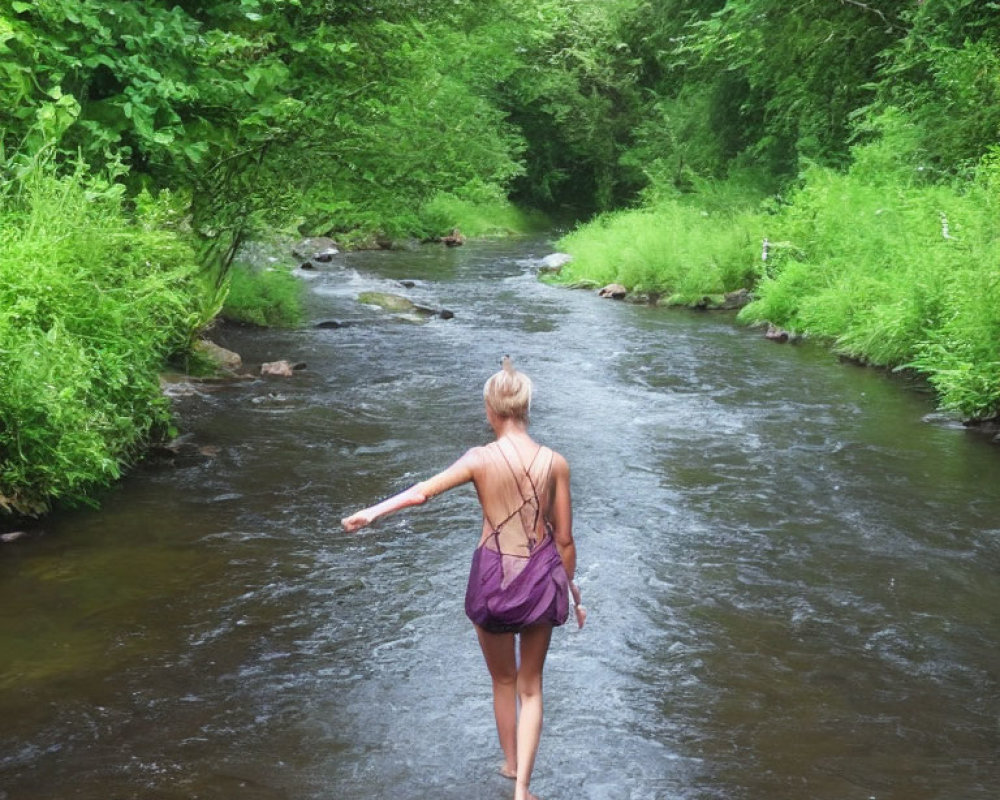 Hiker in backpack wading in stream amid lush greenery