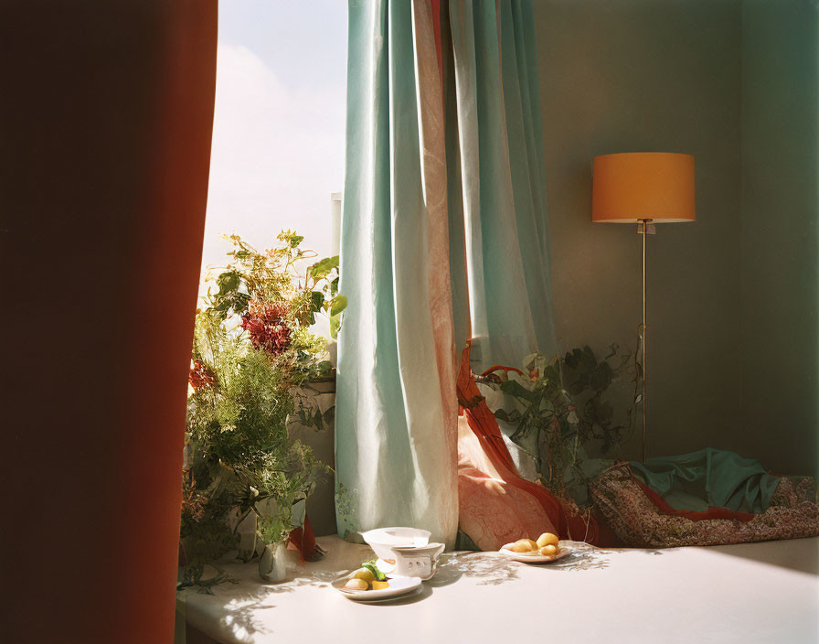 Room corner with tea set, fruit, plants, curtains, and lamp