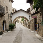 Traditional clothing and market stalls in ancient cobblestone street scene.