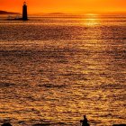 Lone Figure Watching Vibrant Sunset Over Calm Ocean