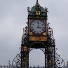 Steampunk clock tower with gears and metalwork against cloudy sky