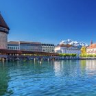 Tranquil waterfront view with houses, tree, and boats on calm blue water