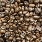 Coffee-themed still life composition with cups, beans, leaves, and berries on brown background