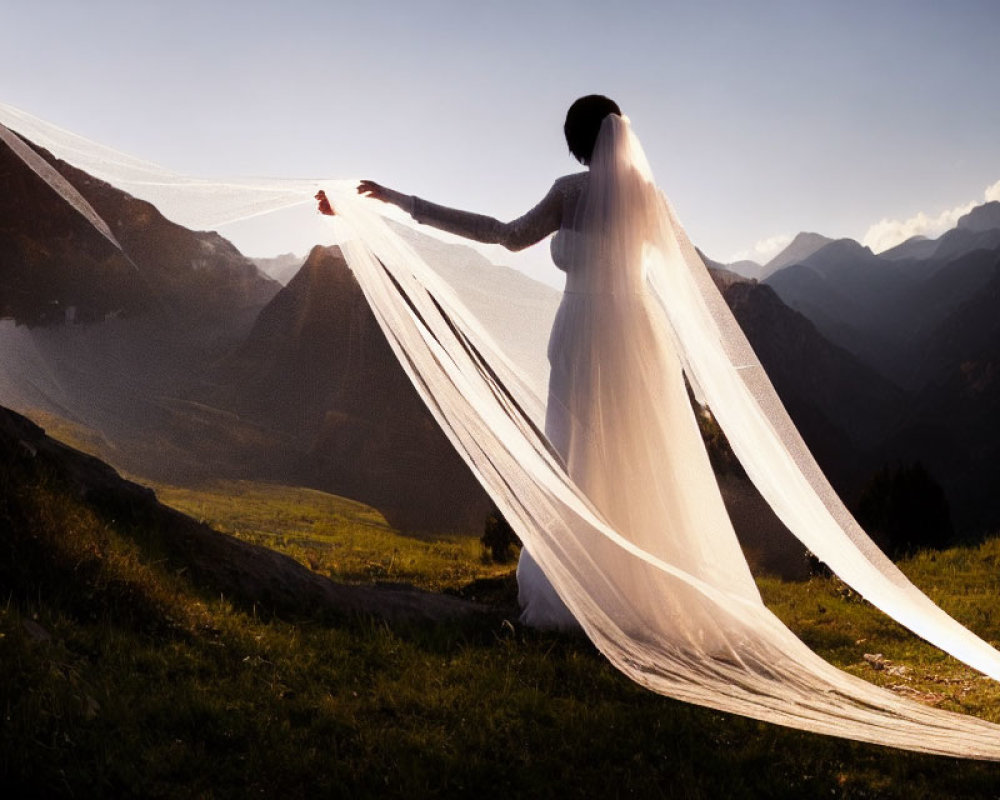 Woman in white dress with flowing veil against mountain backdrop at sunset