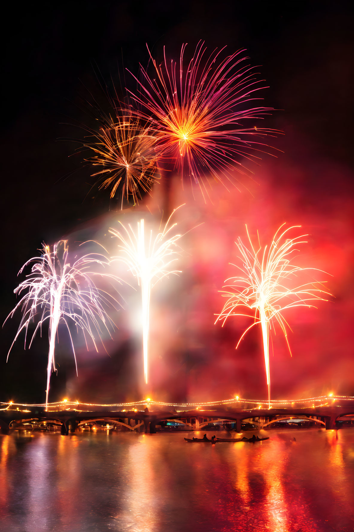 Vibrant fireworks illuminate night sky over bridge and boats