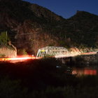 Traditional Japanese garden at night with lanterns, pond, footbridge, and pagodas.