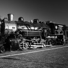 Vintage steam locomotive on tracks with intricate mechanical details against rugged cliffs.