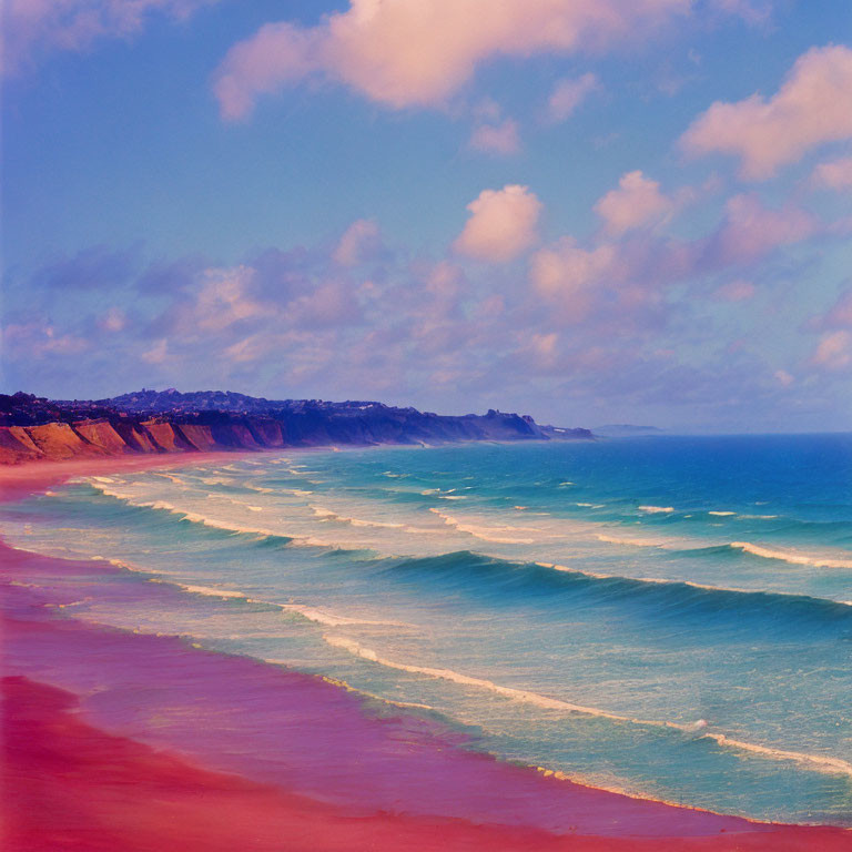 Scenic beach landscape with blue to pink gradient, waves, red cliffs, and cloudy sky