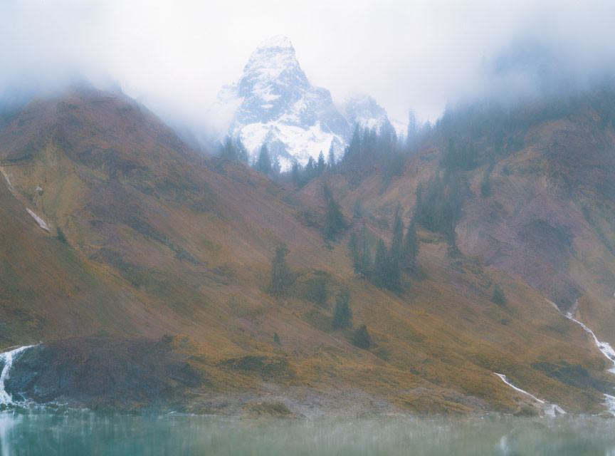 Snow-capped mountain peak in misty alpine landscape