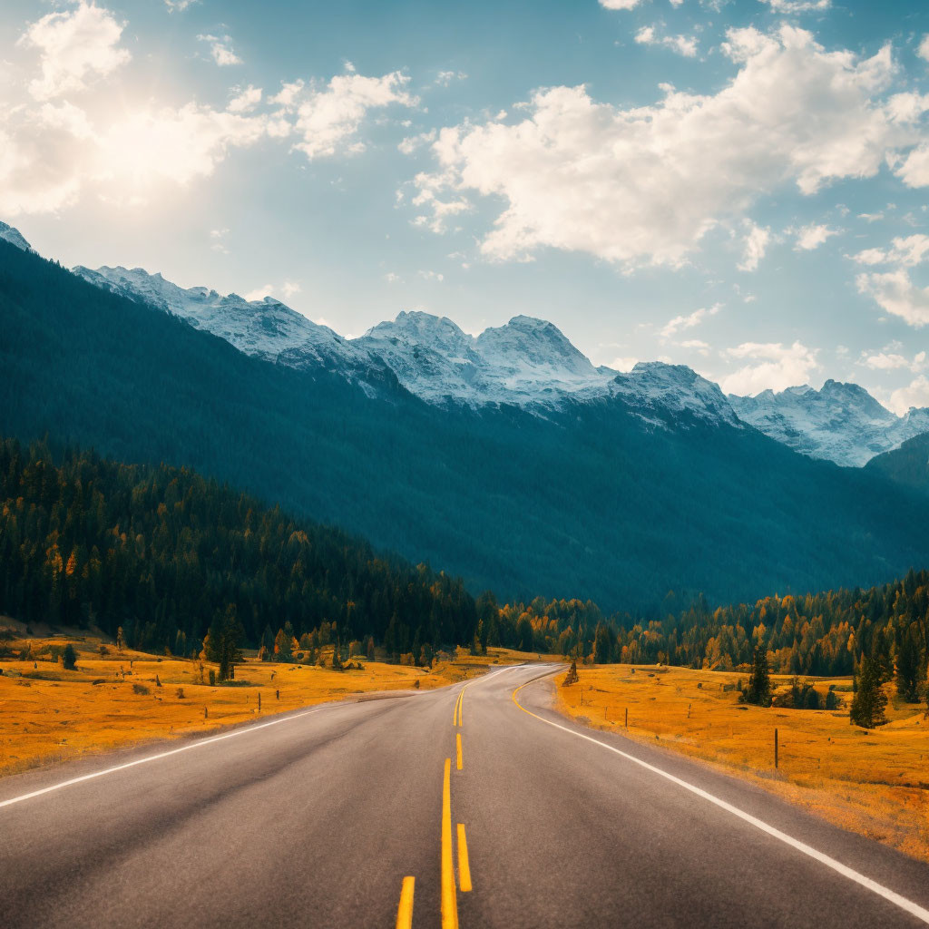 Scenic road amidst autumn trees and snow-capped mountains