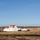 Coastal watercolor painting: white house, lighthouse, rocks, ship.