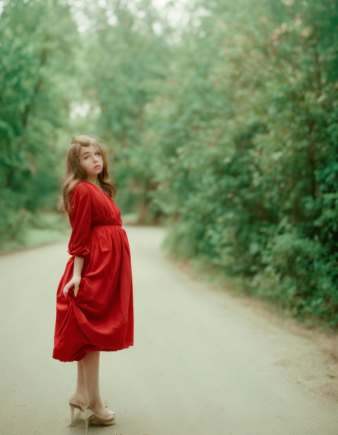 Woman in Red Dress Standing on Dirt Path in Lush Greenery