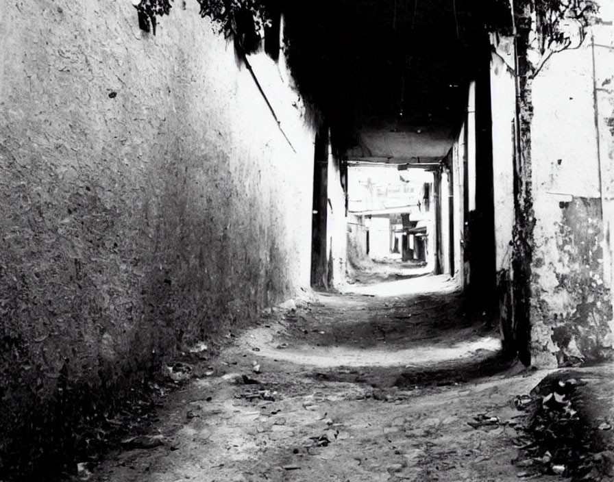 Dark alleyway leading to lighter area with shadows.