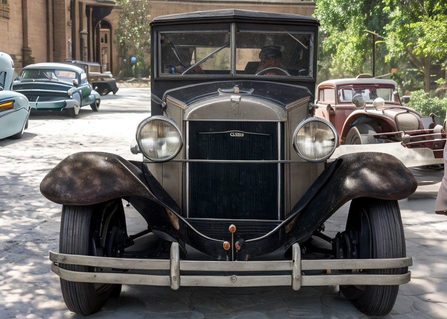 Classic Cars Parked on Cobblestone Street with Large Headlights