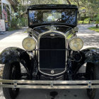 Classic Cars Parked on Cobblestone Street with Large Headlights