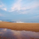 Tranquil beach scene at dusk with colorful sky and people by shoreline